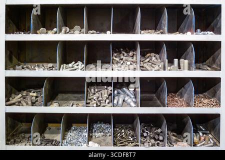 A close-up of an industrial storage rack, with various bolts, nuts, and screws neatly organized in different compartments. Stock Photo