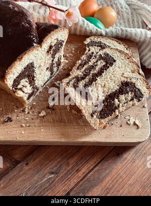 Cozonac, Romanian traditional Easter sweet bread dessert. Cutting sweet bread on a wooden cutting board and Easter eggs on background. Stock Photo
