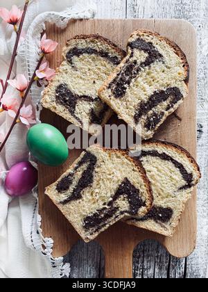 Cozonac, Romanian traditional Easter sweet bread dessert. Cutting sweet bread on a wooden cutting board and Easter eggs on background. Stock Photo