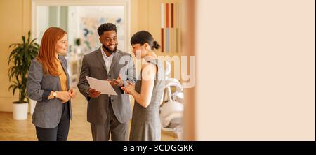Male professional holding documents and brainstorming innovative ideas with female teammates in office Stock Photo