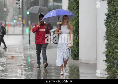 People make their way through the rain in Aldgate, London. Weather warnings have been issued as the fourth heatwave of the summer brings thunderstorms and showers. Picture date: Wednesday August 13, 2025. Stock Photo