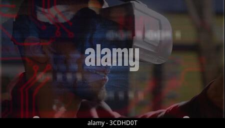 VR user wearing white VR headset exploring tech hub, with red circuit graphic and blurred displays Stock Photo