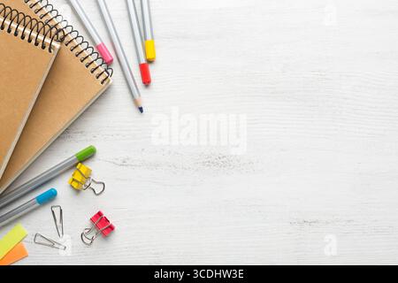 School supplies, colored pencils, notebooks on white shabby wooden table. Back to school concept.  Flat lay. Stock Photo