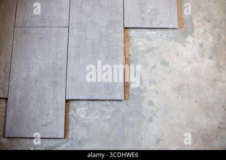 Close-up of large format ceramic tiles being laid on cement screed. Stock Photo