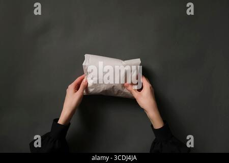 Female Hands Holding Paper Bundle on Dark Gray Table Stock Photo