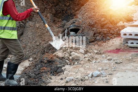 Workers are using shovels to scoop sand into the work area before construction. Stock Photo