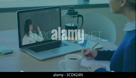 Desk worker writing notes watching colleague drawing graph in office, with laptop tablet and coffee Stock Photo