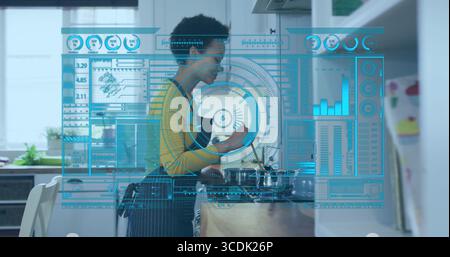 Woman in yellow top and apron stirring pot in home kitchen, interacting with holographic interface Stock Photo