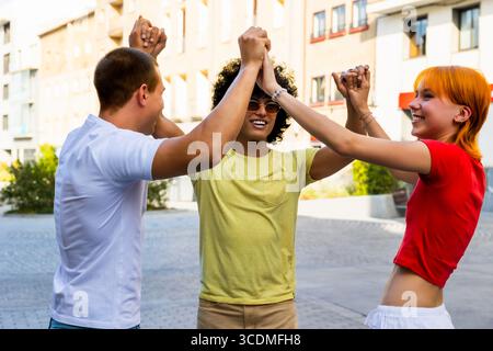 Happy multi-ethnic friends joining hands together in the city Stock Photo