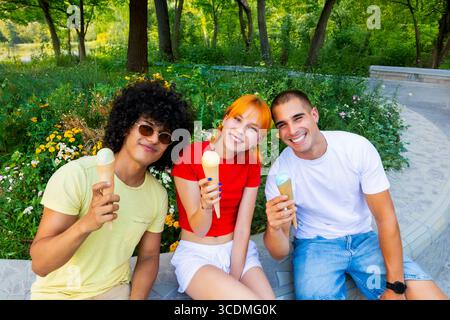 Three friends enjoying ice cream cones in a park Stock Photo