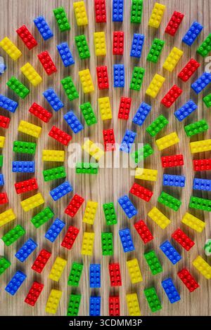 Colorful plastic building blocks arranged in a spiral pattern on a wooden surface. Stock Photo