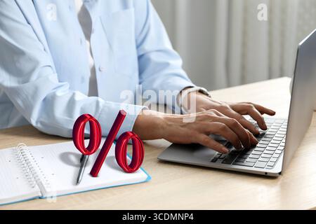 Woman using laptop at table, closeup. Virtual percent sign near her Stock Photo