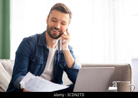Happy businessman working with documents, talking to clients on smartphone Stock Photo