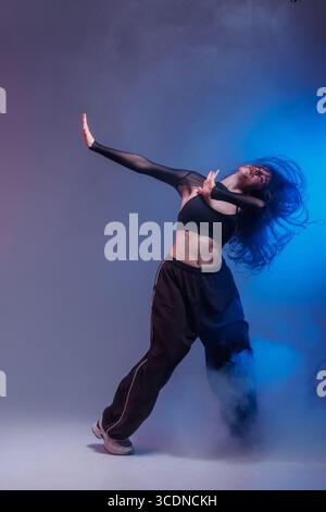 Confident jazz funk dancer in motion with smoke and creative lighting, showing energy and modern urban dance style. Stock Photo