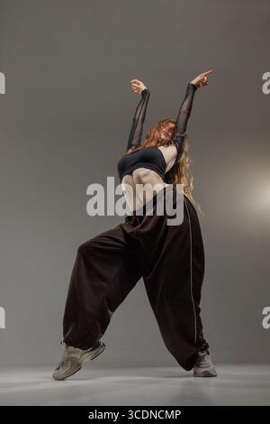 Expressive young dancer in fashionable outfit performing energetic jazz funk move with attitude and style. Stock Photo