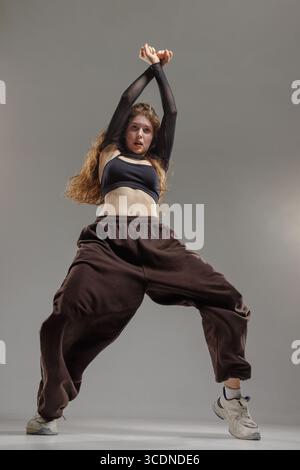 Confident jazz funk dancer in athletic streetwear showing expressive modern moves and powerful energy in studio. Stock Photo