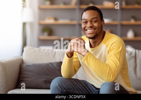 Closeup of positive young black man chilling on sofa Stock Photo