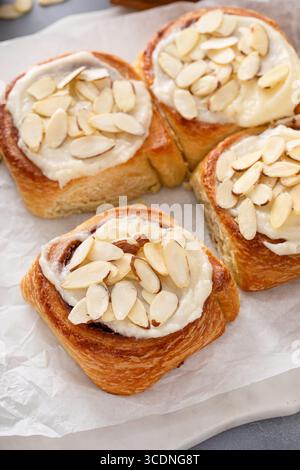 Cinnamon rolls topped with cream cheese frosting and sliced almonds, freshly baked and ready to eat Stock Photo