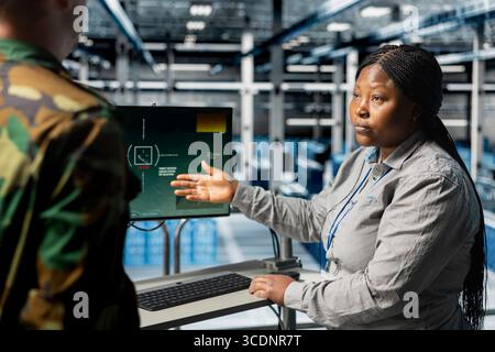 Team of military experts doing brainstorming, looking at encrypted satellite intel in data center. Teamworking army server farm colleagues extracting enemy movement data using satellite technology Stock Photo