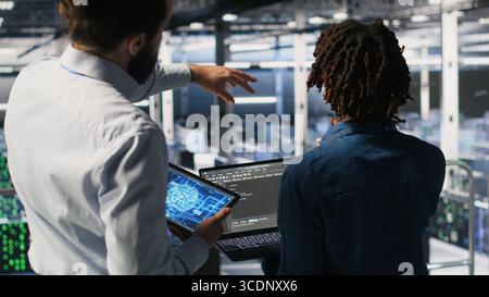 Server farm manager overseeing workers doing infrastructure AI machine learning automatization. Data center team leader supervising employees using artificial intelligence Stock Photo