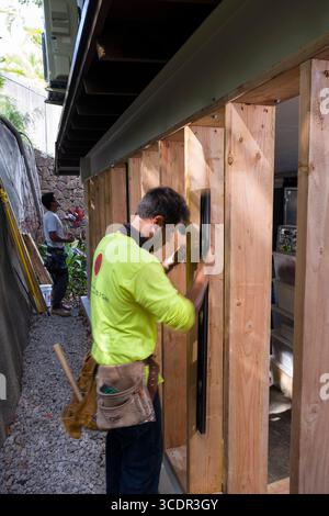 Young man using level to check the plumb of 2x6” lumber during construction, Honolulu, Oahu, Hawaii, USA Stock Photo