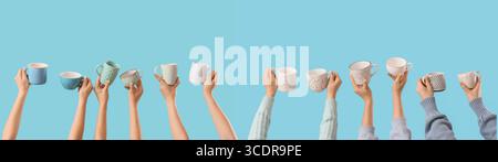 Many hands holding ceramic cups on blue background Stock Photo