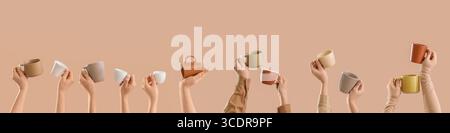 Many hands holding ceramic cups on beige background Stock Photo