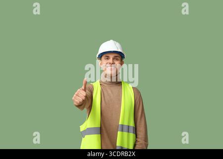 Young male engineer showing thumb-up on green background Stock Photo