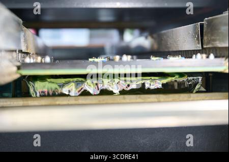 Wave soldering process showing PCB tinning in molten solder bath during manufacturing Stock Photo