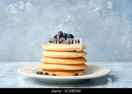 Plate of sweet pancakes with fresh blueberries and blackberries on light blue background Stock Photo