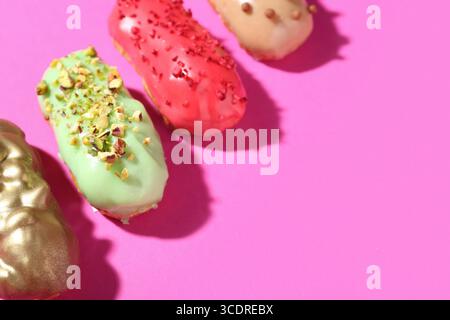 Delicious glazed eclairs on pink background Stock Photo