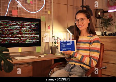 Female programmer with tablet computer in office at night Stock Photo
