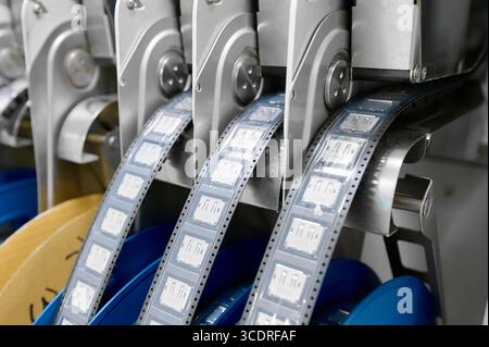 Plastic tape on tape-and-reel packaging machine for SMT components in an industrial setting Stock Photo