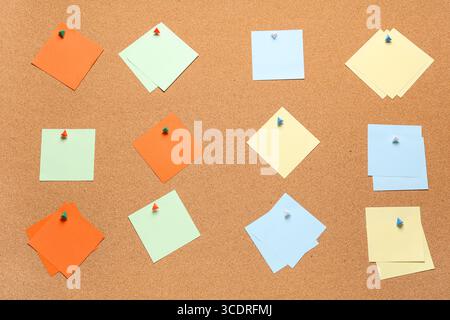 Blank sticky notes with pins on cork board as background Stock Photo