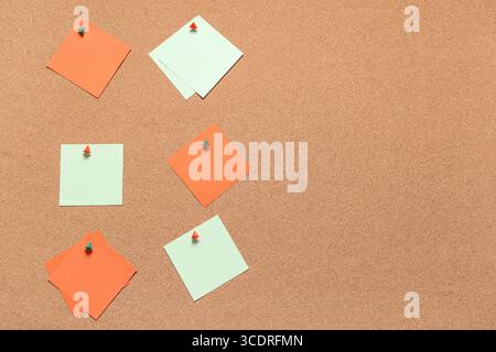 Blank sticky notes with pins on cork board as background Stock Photo