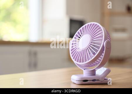 Lilac mini fan on table in kitchen, closeup Stock Photo
