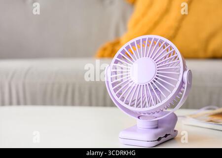 Lilac mini fan on table in living room, closeup Stock Photo