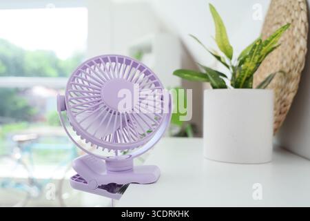 Lilac mini fan on shelf in room, closeup Stock Photo