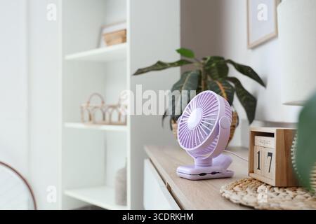 Lilac mini fan on shelf in room, closeup Stock Photo