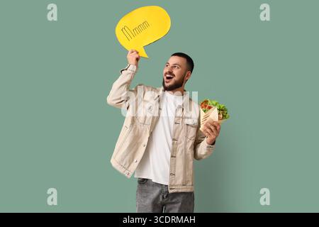 Young man with tasty sandwich wrap and speech bubble on green background Stock Photo