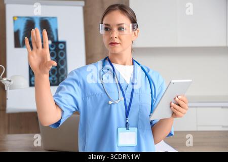 Female doctor in goggles with tablet computer using virtual screen at hospital Stock Photo