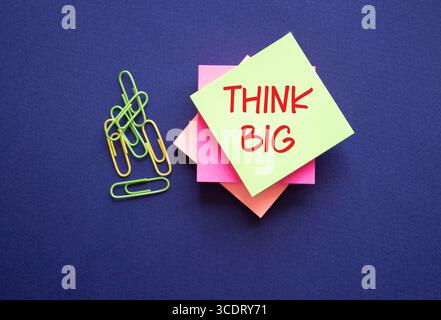 Think big symbol. Yellow sticky note with words Think Big. Beautiful deep blue background. Business and Think big concept. Copy space. Stock Photo