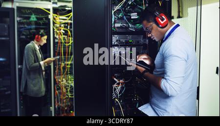 Database, maintenance and tablet with IT professional in server room for cybersecurity support. App, infrastructure and inspection with people in Stock Photo