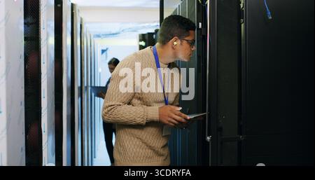 Inspection, maintenance and tablet with IT professional in server room for cybersecurity support. App, database and infrastructure with people in Stock Photo