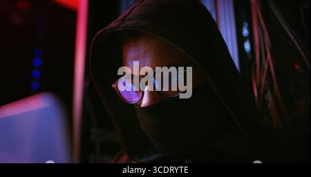 Night, glasses or man on laptop for hacking, programming or cybersecurity website. Software attack, late or hacker with mask in dark room for big data Stock Photo