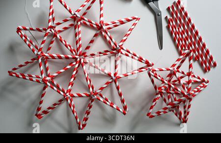 Set of handmade stars in red and white stripe. Different shape. Chaotically placed on white background. Needle, white thread, scissors, paper straws f Stock Photo