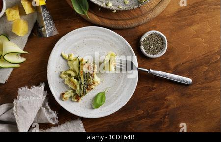 A piece of Vegetable zucchini round pie on the ceramic plate on wooden background, top view Stock Photo