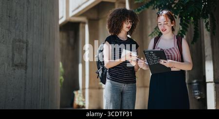 Students engaging in collaborative learning and discussing ideas outdoors at a courtyard Stock Photo