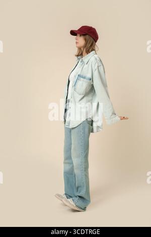 Serie of studio photos of woman in modern casual outfit, blue jeans, white tank top, denim overshirt red red baseball cap Stock Photo