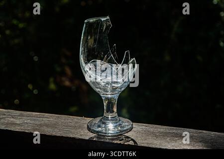 Broken wine glass with shattered pieces inside on a dark blue background Stock Photo